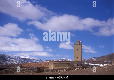 A mosque and minaret set against fresh snow on the Atlas Mountains in Morocco Stock Photo