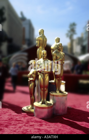 Group of five Oscar statues standing on a red carpet with a black