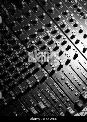 Black and white image of music sound mixing table panel with many knobs buttons switches sliders and other controls Stock Photo