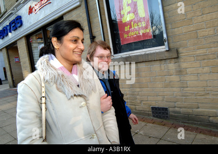 A young man with Downs Syndrome goes shopping with his carer Bradford West Yorkshire Stock Photo