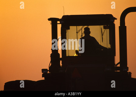 SILHOUETTE OF 4 WHEEL DRIVE CASE IH WITH DISC-HARROW PREPARING FIELD FOR MILO PLANTING AT SUNSET / TEXAS Stock Photo