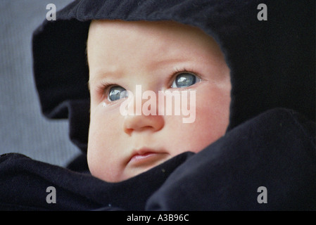 young baby in black hooded sweatshirt, tears in her eyes Stock Photo