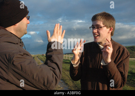 Two men having a conversation in British sign language in the countryside Stock Photo