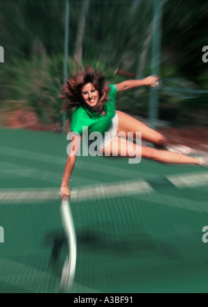 Action Woman leaping over the net on tennis court Stock Photo