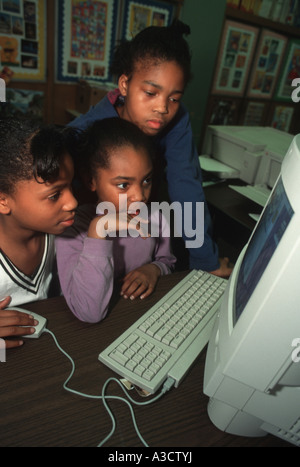 Girls work at a computer together at an inner city public school in Brooklyn Stock Photo