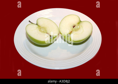 Green apple cut in half on a white plate Stock Photo