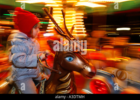 Child riding a red deer on a merry-go-round, Germany Stock Photo