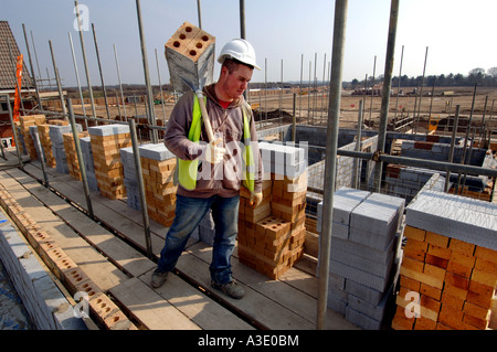A young hod carrier worker on a building site with a load of bricks Stock Photo