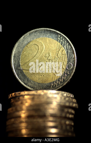 Two Euro coin is standing up to a pile of Euro coins Stock Photo