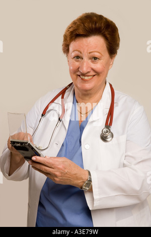 Docotr holds an personal digital device like a PDA. Stock Photo