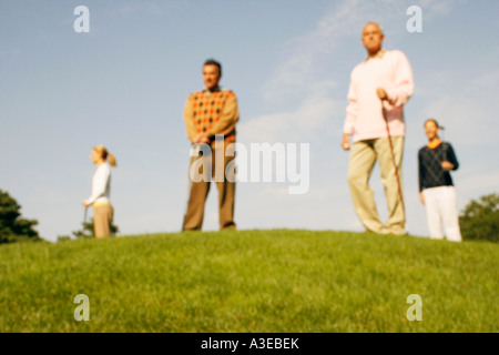 Low angle view of two men and two women standing at a golf course Stock Photo