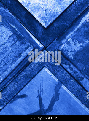 Abstract geometric still life of intersecting weathered steel triangles with blue color cast Stock Photo