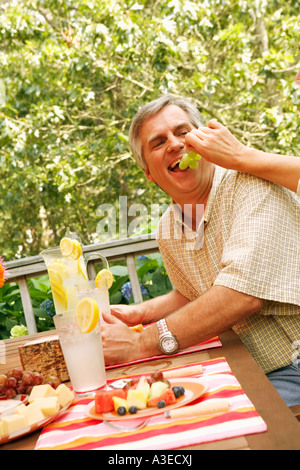 Close-up of a woman's hand feeding grapes to a mature man Stock Photo