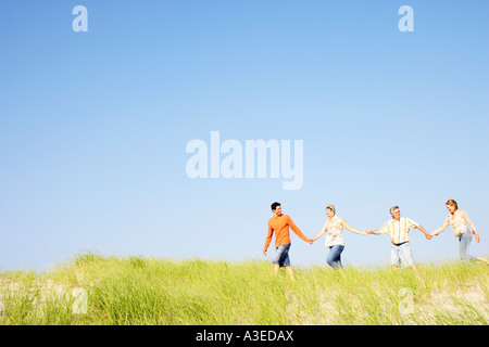 Two mature couples holding hands and walking on the beach Stock Photo