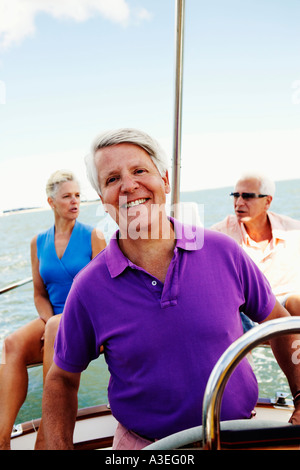 Close-up of a mature man driving a boat with a mature couple sitting behind him