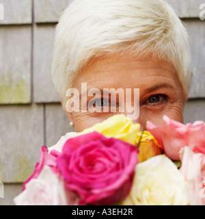 Portrait of a mature woman holding a bunch of flowers in front of her face