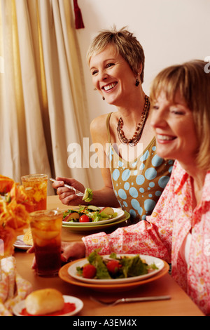 Two mature women sitting at the dining table and smiling Stock Photo