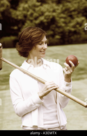 Close-up of a mid adult woman holding a croquet mallet and a ball Stock Photo