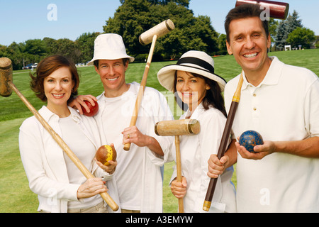 Portrait of a mid adult couple with a mature couple holding croquet mallets and balls Stock Photo