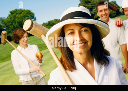 Portrait of a mature woman holding a croquet mallet with a mid adult couple and a mature man standing behind her Stock Photo