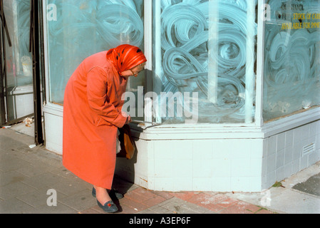 A visually impaired woman using a white stick while out shopping Stock Photo