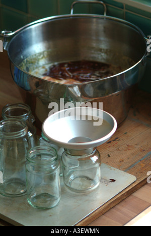 Making Marmalade Metal funnel with jam jars and the marmalade in the background UK Stock Photo