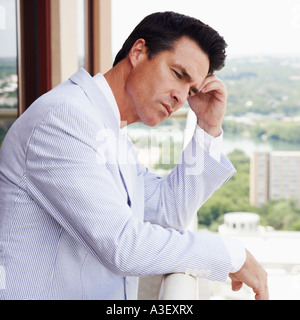 Side profile of a businessman leaning against a railing and thinking Stock Photo