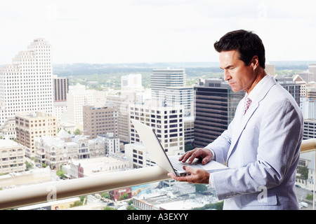 Side profile of a businessman using a laptop in a balcony Stock Photo