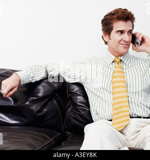Businessman sitting on a couch and talking on a mobile phone Stock Photo