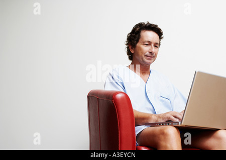 Mature man sitting in an armchair and using a laptop Stock Photo