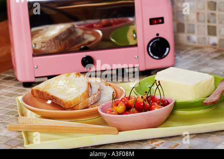 Close-up of cherries with bread and butter in a tray in front of a microwave Stock Photo