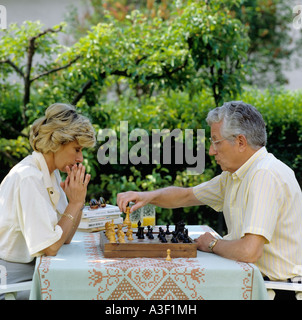 MR MATURE COUPLE PLAYING CHESS IN GARDEN Stock Photo