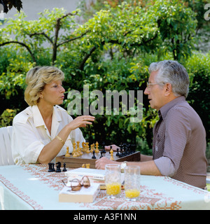 MR MATURE COUPLE PLAYING CHESS IN GARDEN Stock Photo