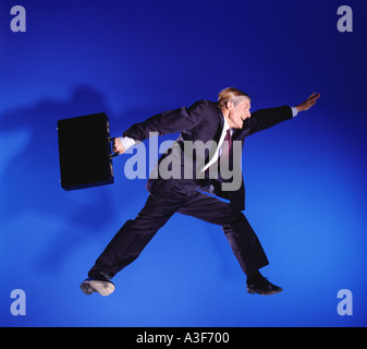 business man jumping in the air blue background Stock Photo