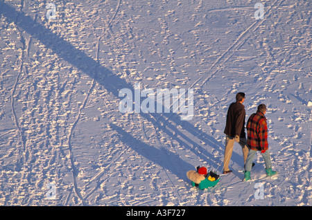 Father pulling child in small sled across frozen waterway in Stockholm Sweden Stock Photo