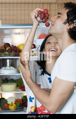 Young woman holding a bunch of plums near a young man's mouth Stock Photo