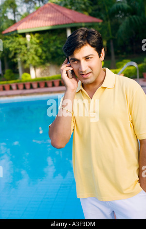 Young man talking on a mobile phone at the poolside Stock Photo