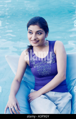 Young woman sitting in an armchair at the poolside Stock Photo