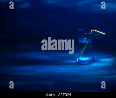 BLUE GLASS WITH GOLDEN STRAW ON HAND PAINTED BLUE BACKGROUND Stock Photo