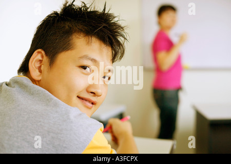 Rear view of a young man sitting in a classroom and smiling Stock Photo