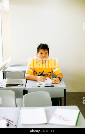 Portrait of a young man writing on a notepad in the classroom Stock Photo