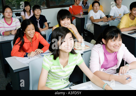 Group of teenage boys and teenage girls sitting in a classroom and smiling Stock Photo
