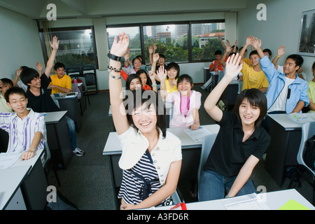 Close-up of students sitting in a classroom and raising their hands Stock Photo
