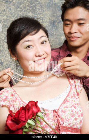 Young man putting a necklace around a young woman's neck Stock Photo