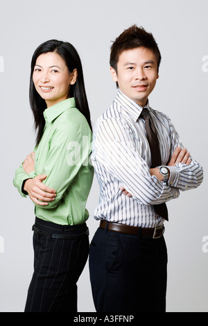 Side profile of a young businessman and a businesswoman standing back to back Stock Photo