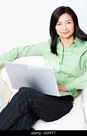 Portrait of a businesswoman sitting in an armchair and using a laptop Stock Photo