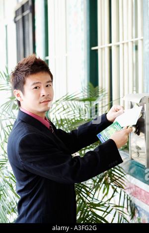 Portrait of a businessman dropping mails into a mailbox Stock Photo