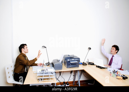 Two businessmen sitting face to face with their hands raised Stock Photo
