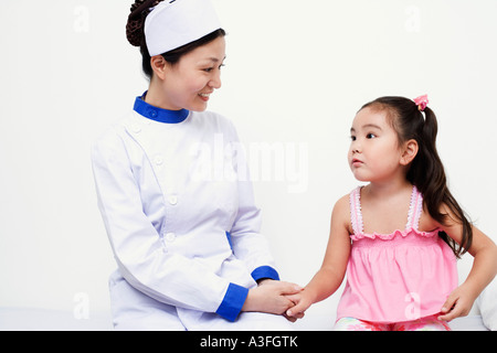 Close-up of a female nurse and a girl child holding hands Stock Photo