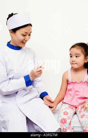 Female nurse holding a syringe with a girl beside her Stock Photo
